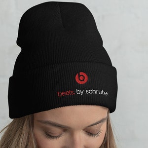 Puede incluir: Gorro negro con un logotipo rojo de Beats by Dre y el texto "beets. by schrute" bordado en blanco.