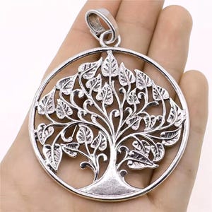 May include: Silver-toned pendant featuring a detailed tree of life design within a circular frame. The pendant showcases intricate leaf and branch patterns, with a loop at the top for a chain. This jewelry piece is suitable for necklaces.