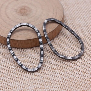 May include: Two black metal oval-shaped rings with a textured surface. The rings are slightly different sizes.