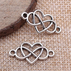May include: Two silver-toned metal charms in the shape of a heart with an infinity knot design. The charms have jump rings for attaching to jewelry or other crafts.