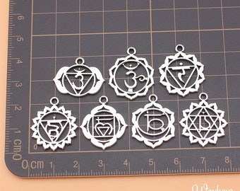May include: Seven silver metal charms with different chakra symbols. The charms are in the shape of a circle with a detailed design. The symbols are the seven chakras: Muladhara, Svadhisthana, Manipura, Anahata, Vishuddha, Ajna, and Sahasrara.