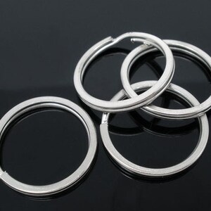 May include: Four silver key rings, interlocking, on a black background.