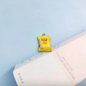 May include: A miniature yellow Lay's Classic potato chip bag charm with a silver metal loop. The bag has a white label with the Lay's logo and the words "Classic" printed on it.