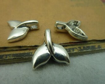May include: Three silver metal whale tail charms. The charms are in the shape of a whale tail, with a loop at the top for attaching to a necklace or bracelet.