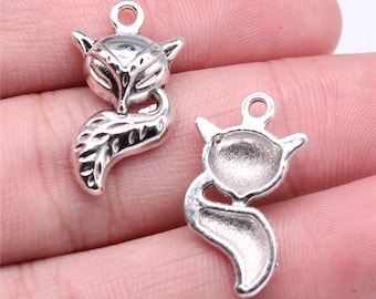 May include: Two silver fox charms with a loop for attaching to a necklace or bracelet. The charm on the left has a detailed design, while the charm on the right is smooth.