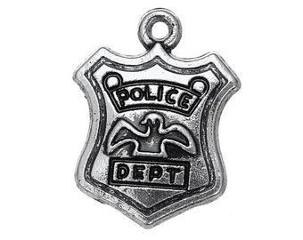 May include: A silver-colored police badge pendant. The shield-shaped charm features the words "POLICE DEPT" and an eagle emblem. The pendant has a loop at the top for attaching to a chain or bracelet.