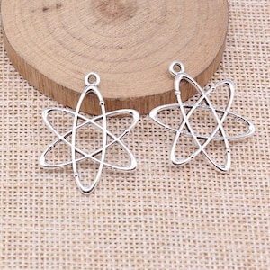 May include: Two silver atom charm pendants with a detailed design. The charms are perfect for jewelry making or crafting.