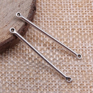 May include: Two silver metal earring findings with a loop at each end. The findings are straight and about 2 inches long.