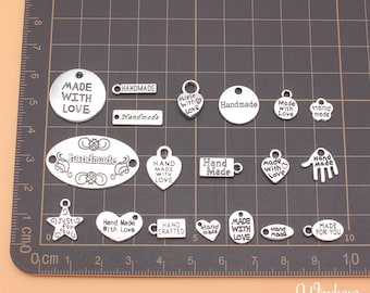 May include: Assortment of silver metal charms with various phrases and designs, including "Made with Love", "Handmade", "Hand Made", "Just for You", and "Hand Crafted".