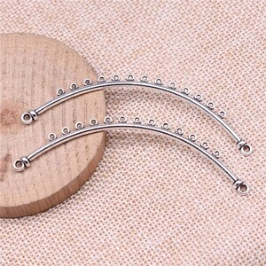 May include: Two silver-toned metal hoops with small circles along the top edge. The hoops are curved and have a rounded end.