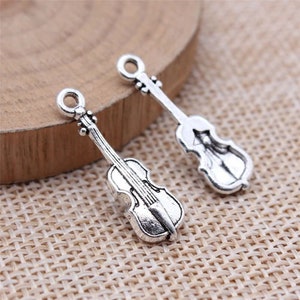 May include: Two silver-toned violin charms with a detailed design. These charms are perfect for adding a musical touch to jewelry or crafts.