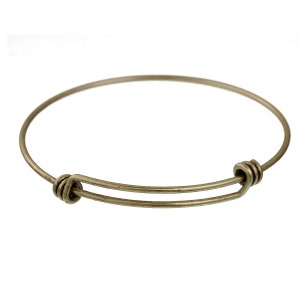 May include: A simple, expandable bangle bracelet made of silver-toned metal. The bracelet has a smooth, polished finish and a secure clasp.
