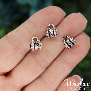 May include: Three silver metal bead caps with a decorative design. The caps have a small loop at the top for attaching to jewelry.