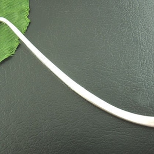 May include: A silver bookmark with a curved end. The bookmark is made of metal and has a smooth, polished finish.