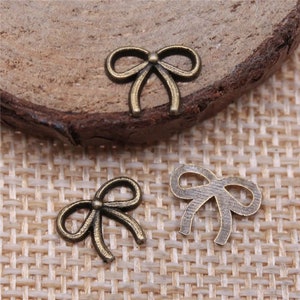 May include: Three antique gold-toned metal bow charms. The bows are delicate and have a slightly distressed finish.