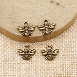 May include: Four antique gold bee charms with a loop for attaching to jewelry or crafts.