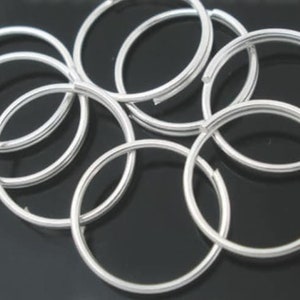 May include: A group of silver jump rings, a type of metal ring used in jewelry making.
