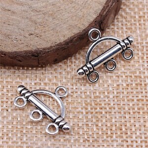 May include: Two silver-toned metal clasps with three loops each. The clasps are shaped like a half-circle with a straight bar across the center.