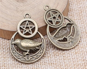 May include: Two antique bronze pendant charms featuring a five-pointed star, a crescent moon, and a raven. The charms are intricately detailed and have a rustic, vintage aesthetic.