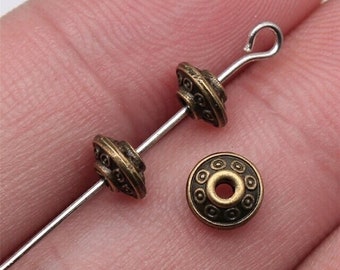 May include: Three antique gold-toned metal beads with a decorative design. The beads are strung on a silver wire with a loop at the end.