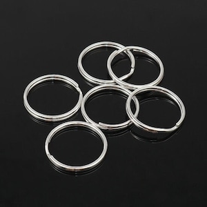 May include: A set of eight silver key rings. The key rings are all the same size and shape, and they are arranged in a circle.