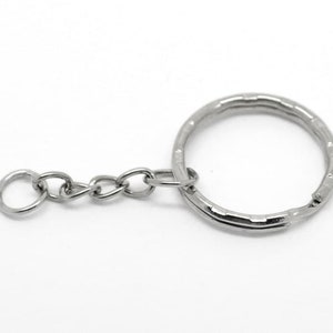 May include: A silver key chain with a round ring and a small chain attached.