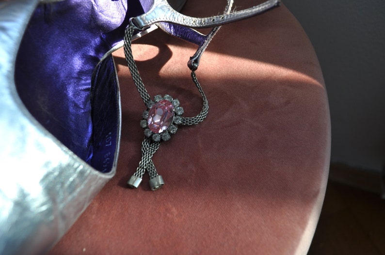 Peut inclure: Une chaussure argent&eacute;e avec une doublure violette et un bracelet de cheville en strass rose. Le bracelet est de conception en cha&icirc;ne et comporte un grand strass rose au centre.