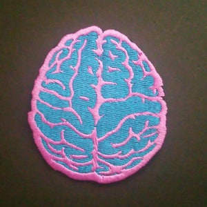 May include: A pink and blue embroidered brain patch. The brain is outlined in pink and filled in with blue.