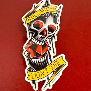 May include: A sticker featuring a skull with a crown, holding a red and black die. The skull has red eyes and is dripping. Yellow banners read "ROLL HIGH" and "DON'T DIE".