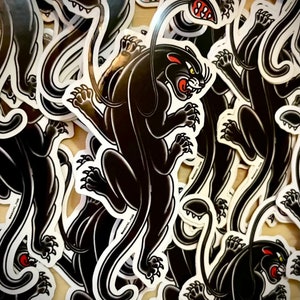 May include: A stack of black panther stickers with white outlines. The panthers are in a classic tattoo style with a curled tail and a fierce expression.