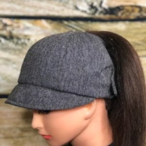 La gorra de tweed negra estilo jockey para mujer tiene una abertura alta para sujetarla con una cola de caballo sin necesidad de pasadores ni pinzas.