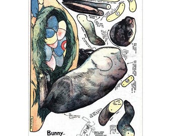 May include: Vintage paper craft sheet featuring a bunny design with various cut-out pieces. The illustration includes a bunny's body, ears, and tail, with instructions and a diagram. The color palette includes shades of blue, green, and yellow.