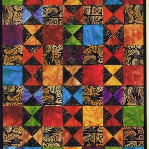 May include: A quilt block pattern with a black background and colorful squares. The squares are in shades of red, orange, yellow, green, blue, and purple. The squares are arranged in a grid pattern.