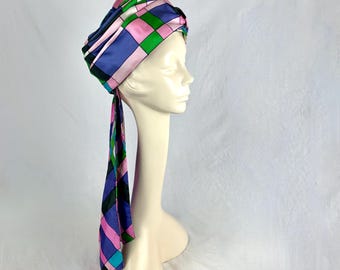 May include: A purple, pink, green, and black patterned turban with a long tail.