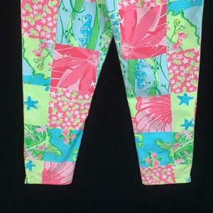 Pu&ograve; includere: Un paio di pantaloni rosa, blu e verdi con un design a patchwork che presenta cavallucci marini, fiori e stelle marine.