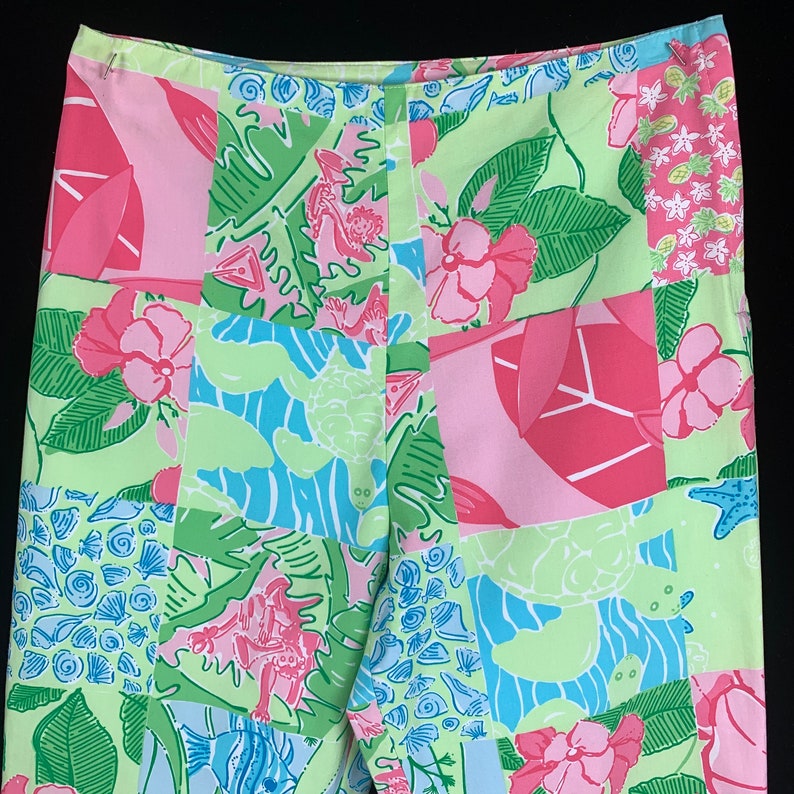 Pu&ograve; includere: Un paio di pantaloni rosa e verdi a patchwork con una stampa di tartaruga marina, pesce e fiori.