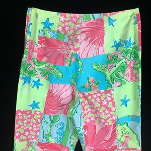 Pu&ograve; includere: Un paio di pantaloni patchwork verde, rosa e blu con stampa floreale e tropicale. I pantaloni hanno una chiusura a zip e una tasca posteriore.
