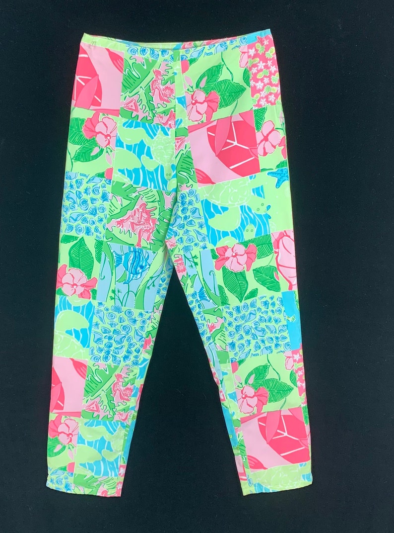 Pu&ograve; includere: Un paio di pantaloni a gamba dritta e vita media con un design a patchwork verde, rosa e blu.