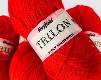 May include: Red yarn balls labeled "Hartfield Trilon 3-Ply Fingering"