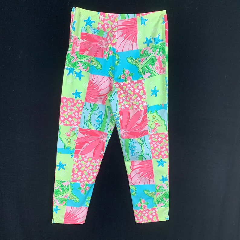 Pu&ograve; includere: Un paio di pantaloni a gamba dritta di colore verde, rosa e blu con un motivo a patchwork. I pantaloni hanno una vestibilit&agrave; rilassata.