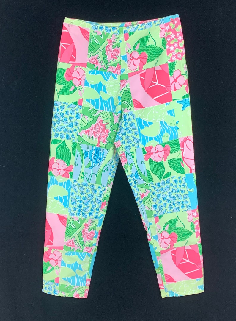 Pu&ograve; includere: Un paio di pantaloni a gamba dritta e vita media con un design a patchwork verde, rosa e blu.
