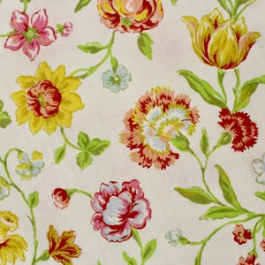 May include: A white fabric with a floral pattern featuring yellow, red, pink, and green flowers. The flowers are arranged in a repeating pattern on the fabric.