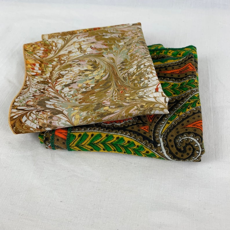 Peut inclure: Deux carr&eacute;s de tissu avec des motifs diff&eacute;rents. Le carr&eacute; du haut est de couleur brun clair avec un motif marbr&eacute; en spirale. Le carr&eacute; du bas est de couleur brun fonc&eacute; avec un motif paisley en vert, orange et blanc.