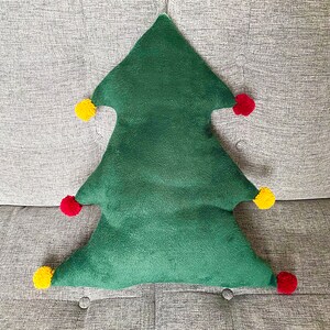 May include: A green plush Christmas tree pillow with red and yellow pom-poms.
