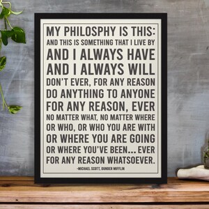 以下が含まれることがあります： マイケル・スコットの「MY PHILOSOPHY IS THIS」という引用句が書かれた黒いフレームのプリント。テキストはオフホワイトの背景に黒色です。プリントは木製の表面に表示されています。
