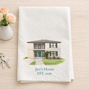 May include: White kitchen towel with a watercolor illustration of a two-story house. The text "Jen's House EST. 2026" is printed in teal. A small vase of roses and a set of keys are on the table.