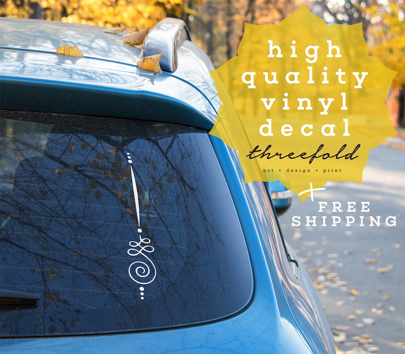 May include: A blue car with a white vinyl decal on the back window. The decal features a stylized design with a spiral and dots. The text "high quality vinyl decal threefold art + design + print FREE SHIPPING" is on a yellow background.