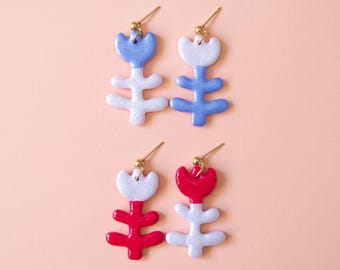 Pendientes de flores asimétricos: hechos a mano en arcilla y resina, con detalles de purpurina.
