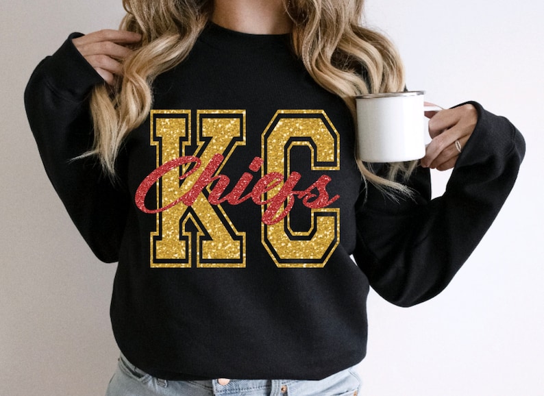 Op de afbeelding: Zwart sweatshirt met gouden glitter "KC Chiefs" belettering.