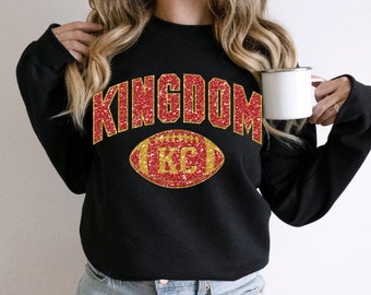 May include: Black sweatshirt with red glitter lettering that says "KINGDOM" and a red and gold glitter football with "KC" inside.
